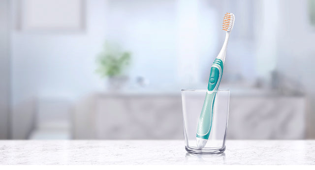 Single TRISA Sonicpower toothbrush standing upright in a glass, highlighting minimalist Swiss design.